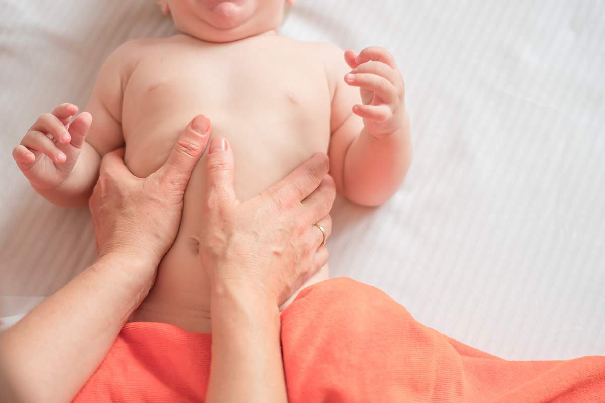 Un bébé souriant pendant une séance de massage, accompagné par sa maman